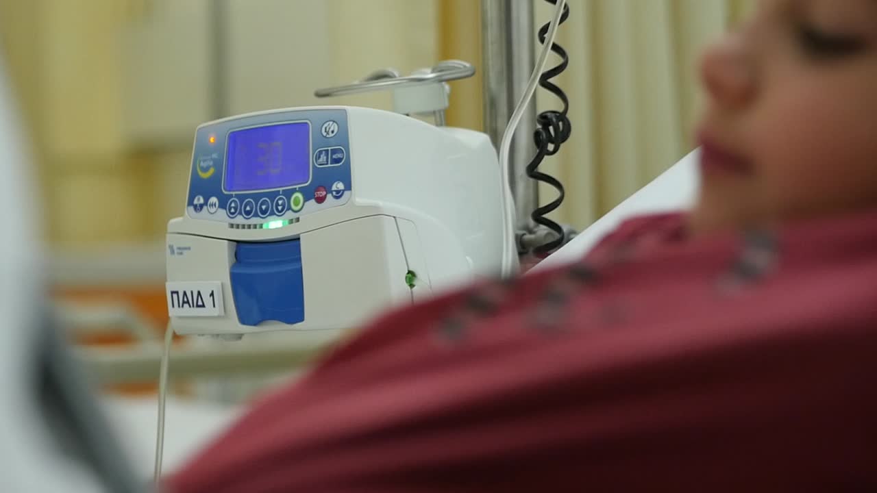 병원 침대에 있는 아이가 생명 통계 모니터에 연결되어 있습니다.