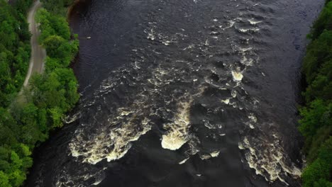 Drone-shot-of-the-Gatinueau-River-in-Quebec-Canada-panning-up-following-the-flow-of-water-with-cottages-visible-on-the-river-banks
