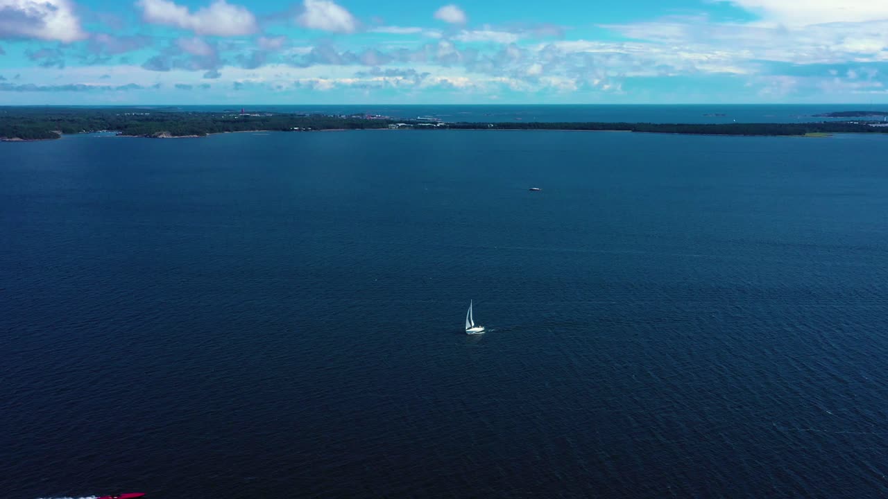 Aerial view of a white sailboat on the open sea, at the Gulf of Finland, bright, sunny, summer day, near Hanko, in Uusimaa, Finland - tracking, drone shot