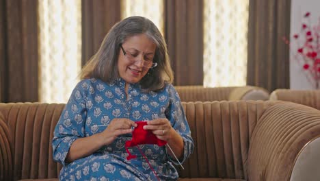 happy aged indian woman knitting a sweater