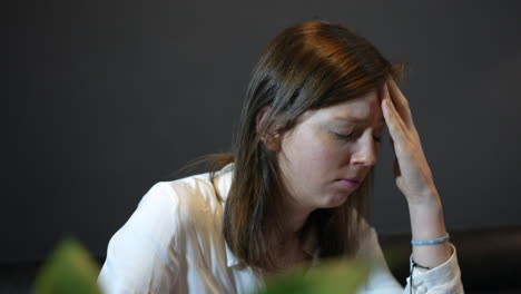 an upset sad young woman shaking her head and rubbing her head in frustration looking pensive and depressed