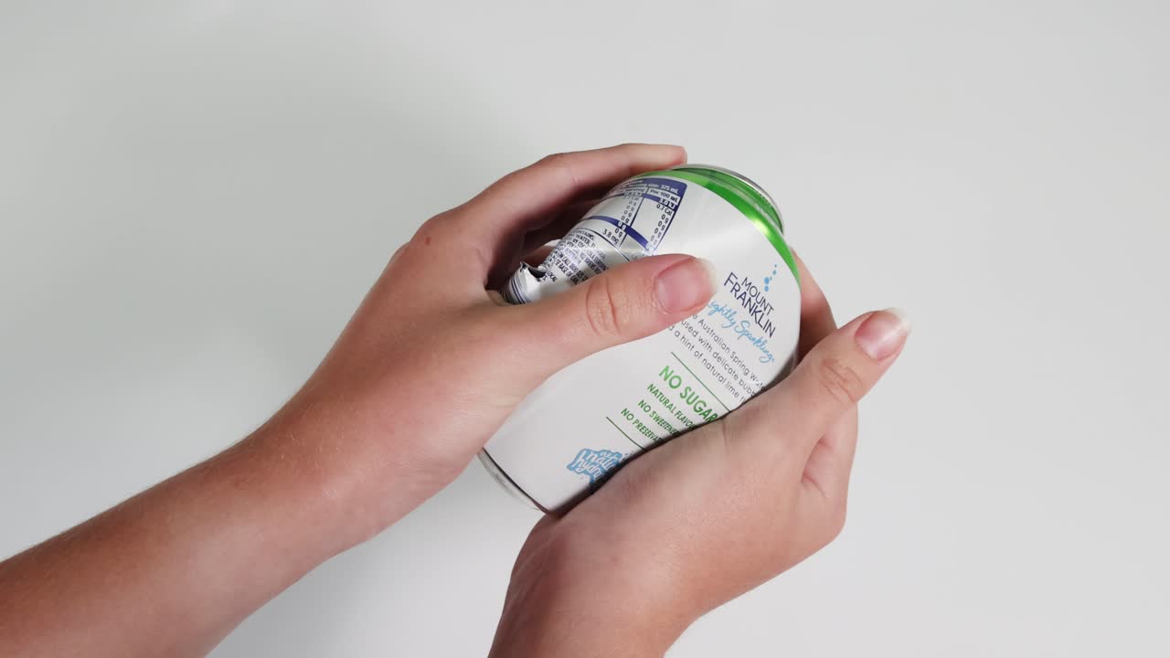 apretando y aplastando con la mano una lata de refresco