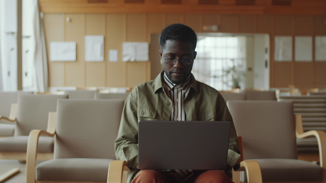 hombre afroamericano usando una computadora portátil en el auditorio de la biblioteca