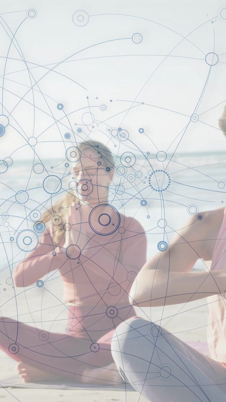 Vertical video: Two women meditating beachside blue dot sparking rings over them for health