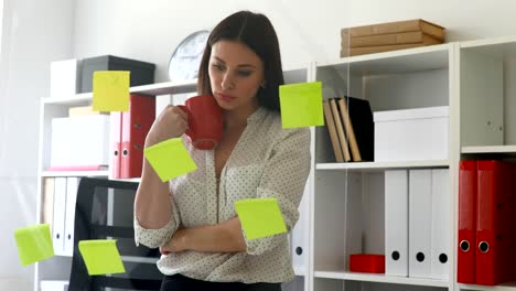 businesswoman in white blouse considering stickers on glass in office