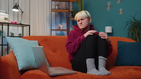 woman working on her laptop while sitting on a couch in her living room