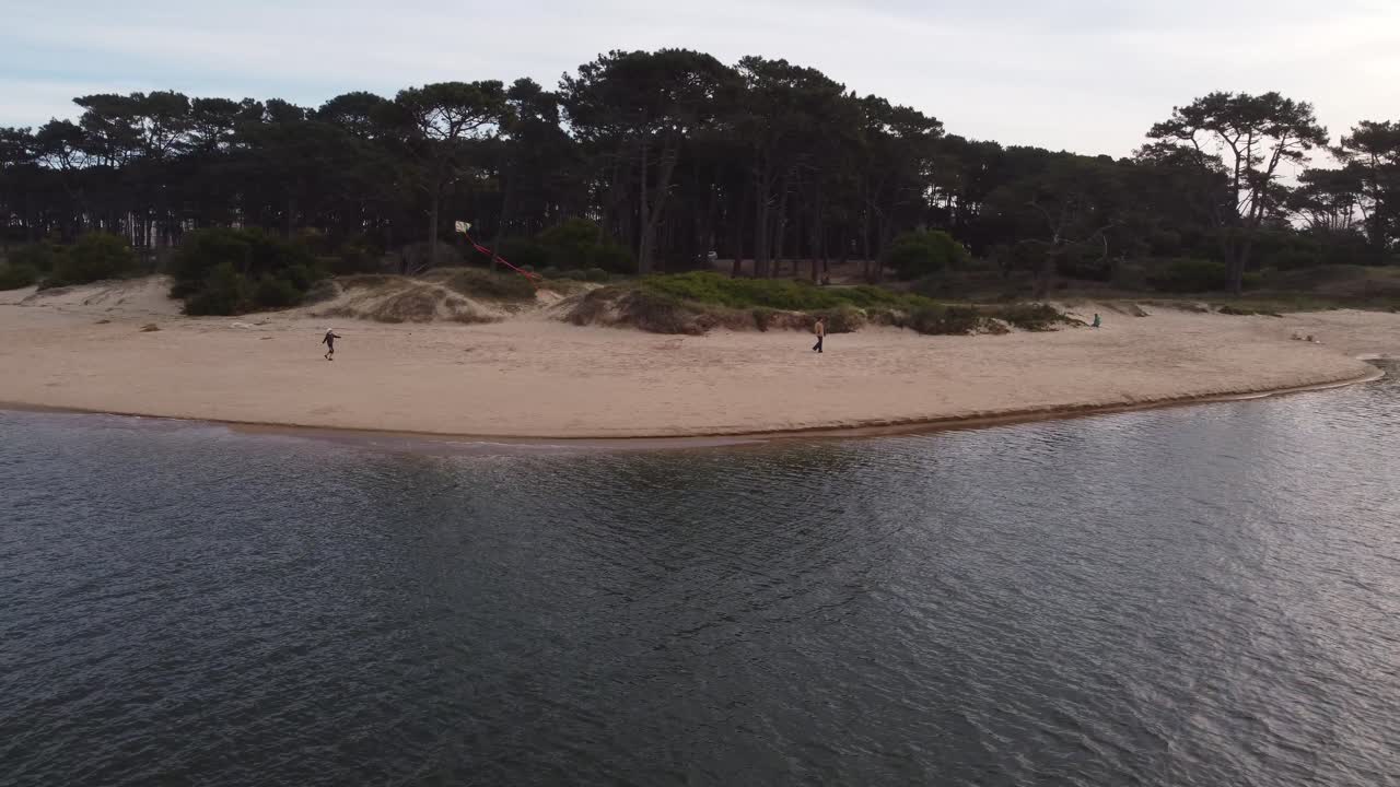 Ripresa con drone di un giovane ragazzo che fa volare un aquilone sulla riva sabbiosa del fiume Maldonado, Uruguay.