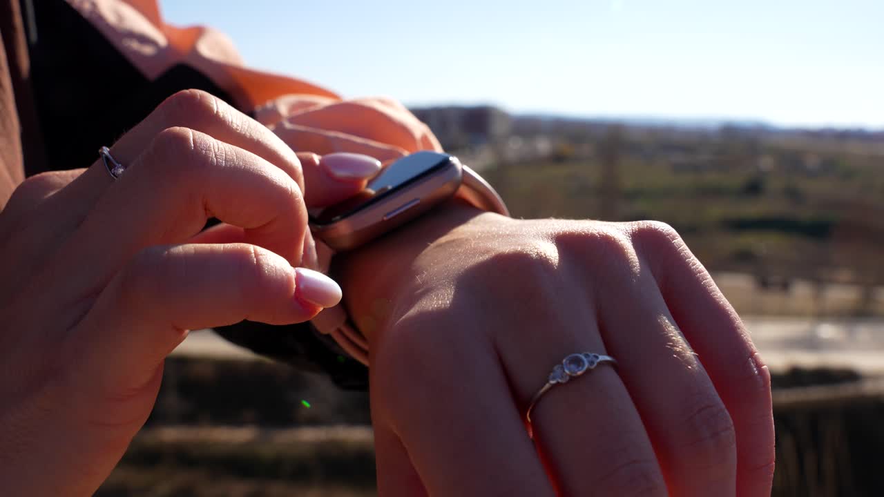 una corredora ajustando los parámetros de su reloj inteligente.