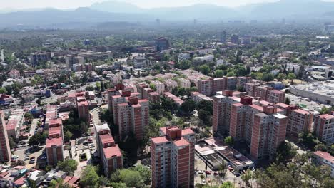 Aerial-flight-over-housing-units-in-Coyoacan,-south-of-Mexico-City,-with-the-university-campus-in-the-background