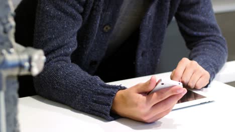 Mid-section-of-man-using-digital-tablet-and-mobile-phone