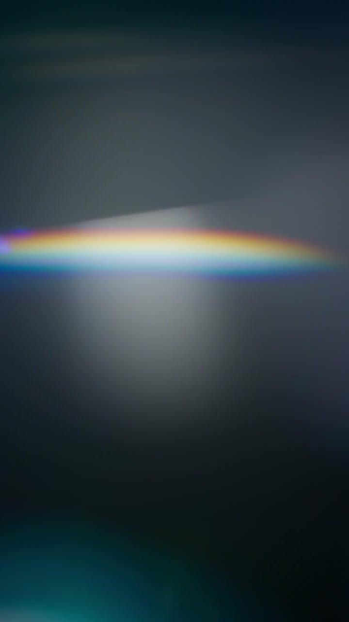 Fughe di luce astratte create dal riflesso di un prisma di vetro con colori arcobaleno.