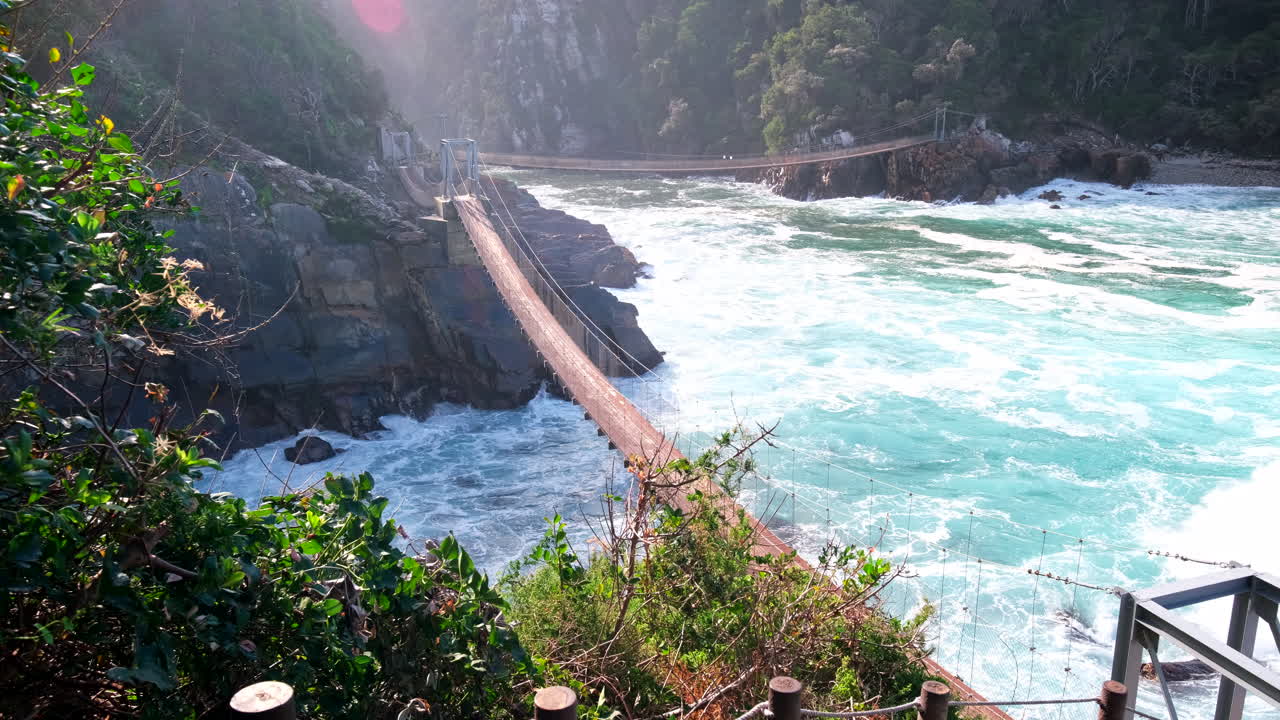 Frothing sea waves roll in under suspension footbridge at Storms River mouth