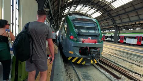 travelers approach train at milan railway station