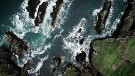 Luftaufnahme-Von-Oben,-4K-Aufnahmen-Per-Drohne-Von-Ozeanblauen-Wellen,-Die-Auf-Einer-Hohen-Klippe-Eines-Felsigen-Berges-Brechen