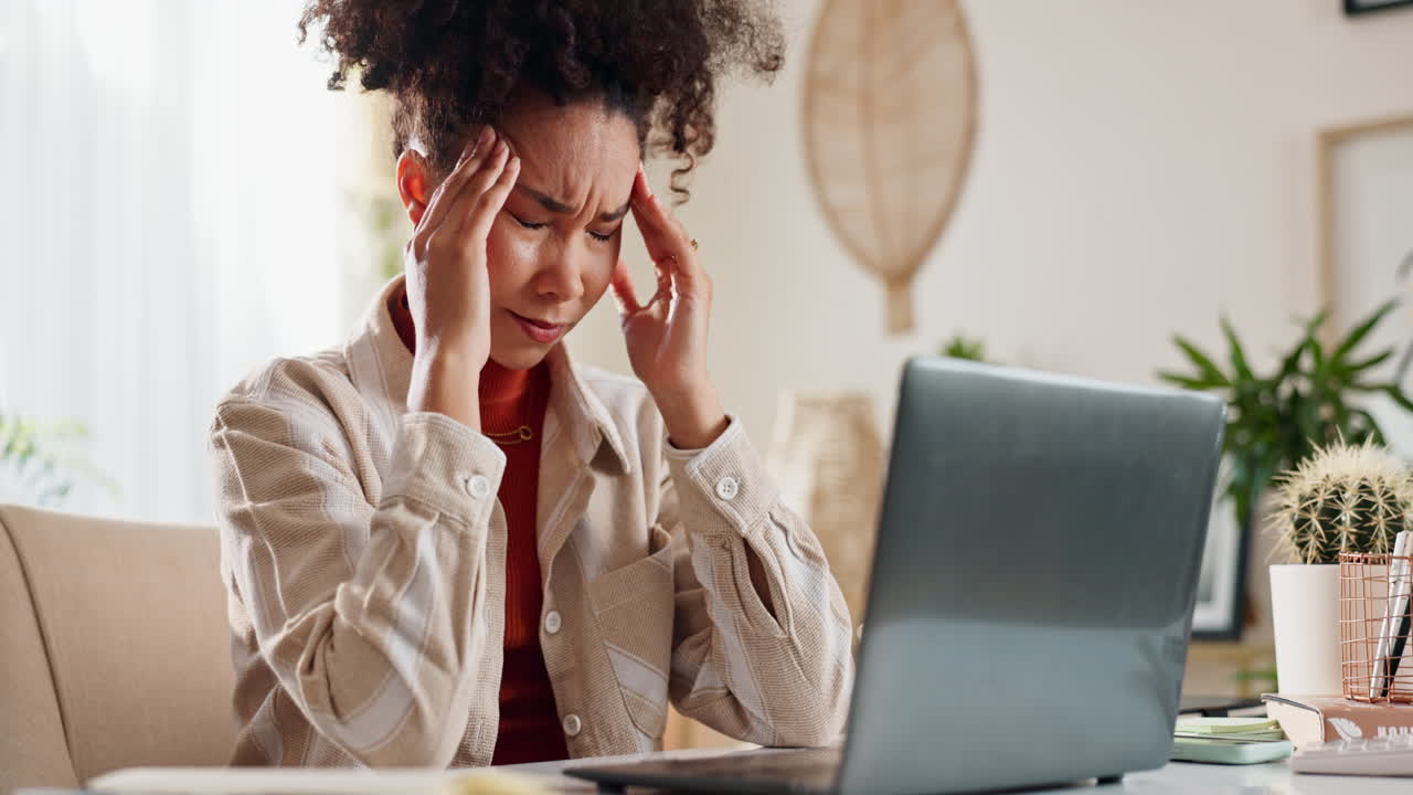 Woman experiencing headache while working from home