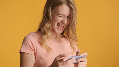 una mujer caucásica jugando videojuegos en su teléfono inteligente.