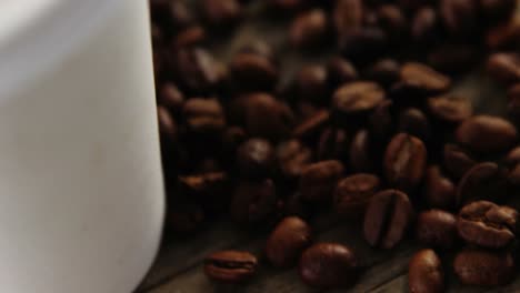 Disposable-cup-with-coffee-beans-on-wooden-plank