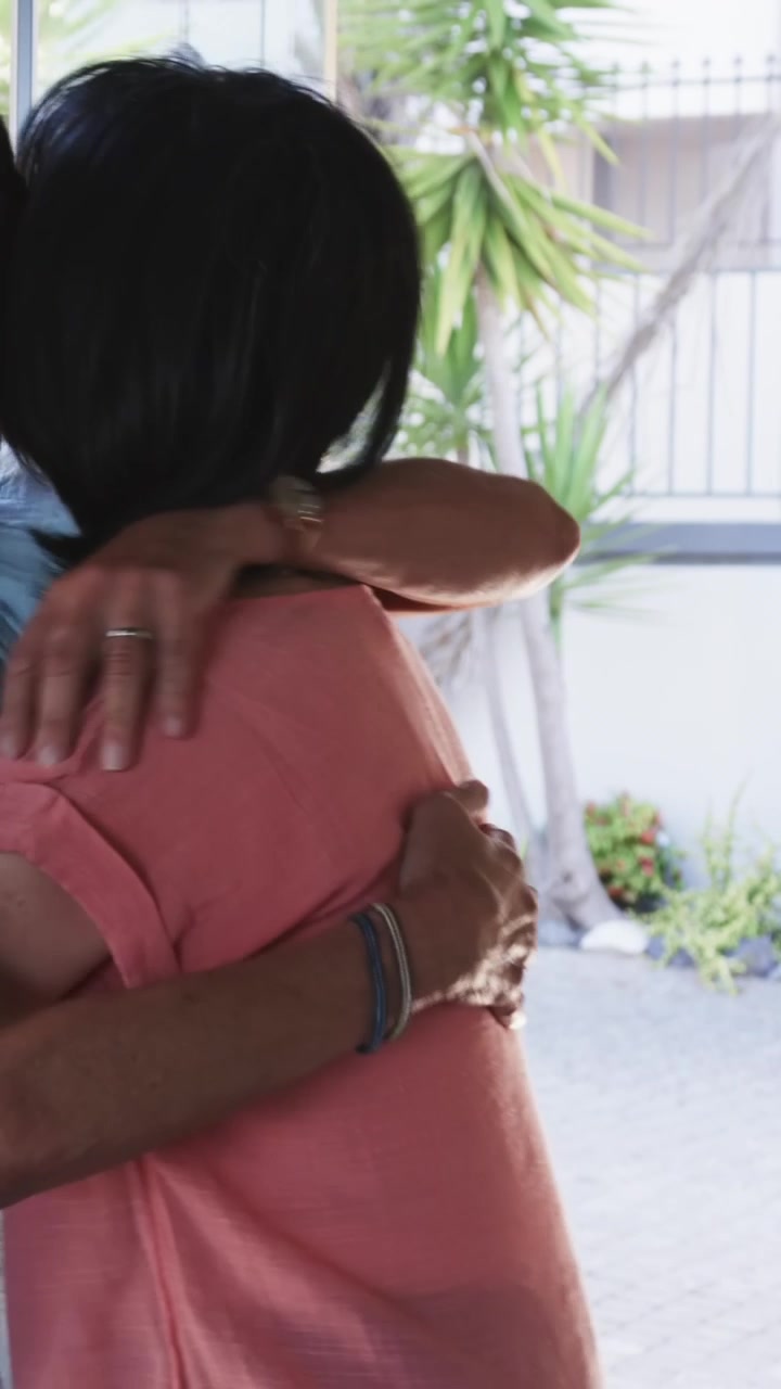 Video verticale: Donne anziane entrano in casa mentre una persona tiene aperta la porta a vetri, si abbracciano, con spazio per il testo.