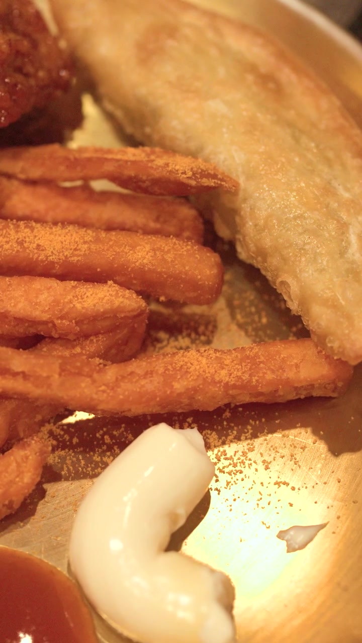 Primer plano de pollo frito crujiente, patatas fritas sazonadas y empanadillas en un plato de latón