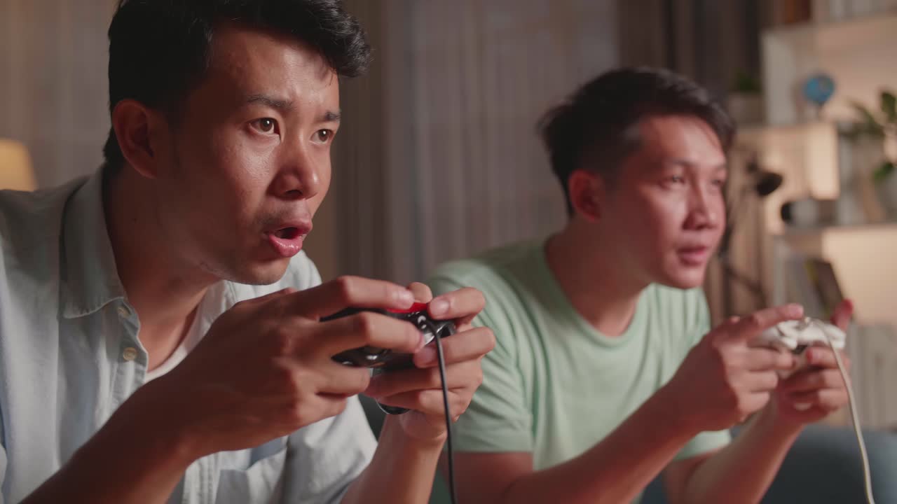 Asian Friends With Joystick Playing Video Games And Celebrating Victory At Home