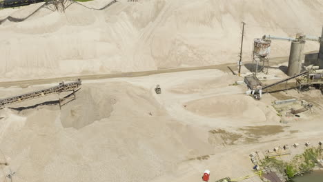 tractor driving through heap of sand at sand and gravel plant in van buren, arkansas