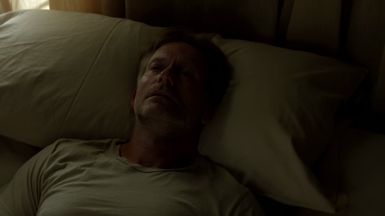 Middle-aged Man Lying Awake in Bed in a Dark Room