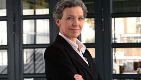 mature businesswoman standing with arms crossed and smiling at the camera