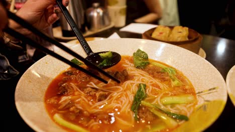 person eating noodles with chopsticks in melbourne restaurant