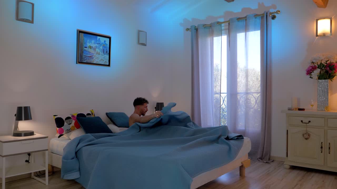 dolly shot of a man waking up and sitting on the side of his bed