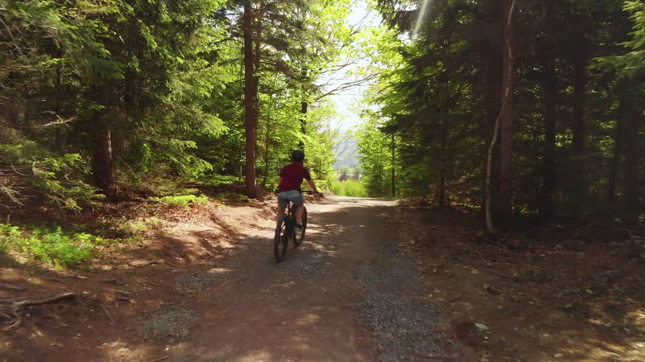 Aerial dolly shot of the mountain bike rider in the woods