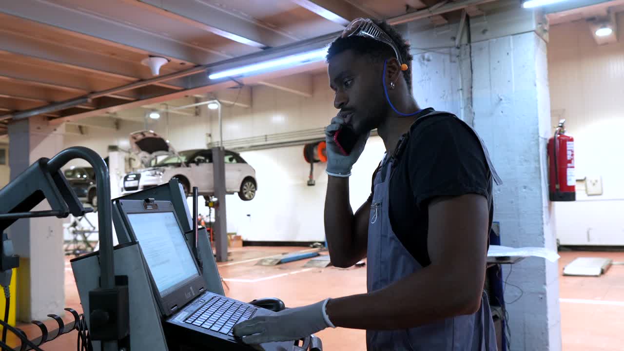 Mechanic using laptop and talking on the phone in a car repair shop