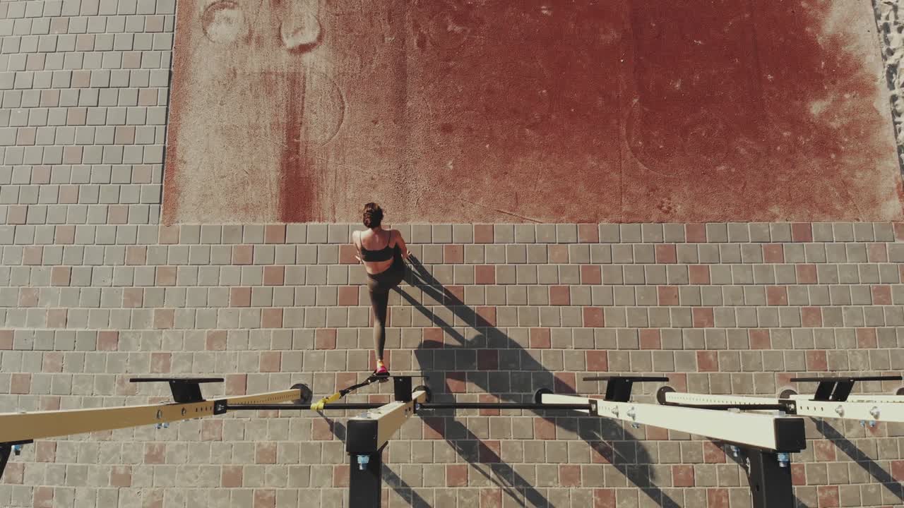 entrenamiento al aire libre. correas de suspensión. aero vista superior. mujer joven atlética está haciendo ejercicios de resistencia de todo el cuerpo usando cuerdas en bucle trx, en el campo deportivo al aire libre de la ciudad, gimnasio. entrenamiento de fitness al aire abierto. concepto de estilo de vida saludable. entrenamiento deportivo matutino en el