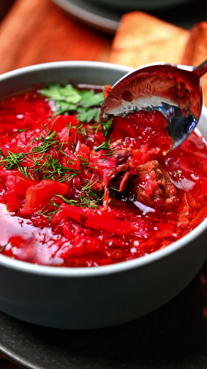 Traditional borscht soup with spoon and herbs. Red beet soup with herbs and rich flavor served in bowl with spoon