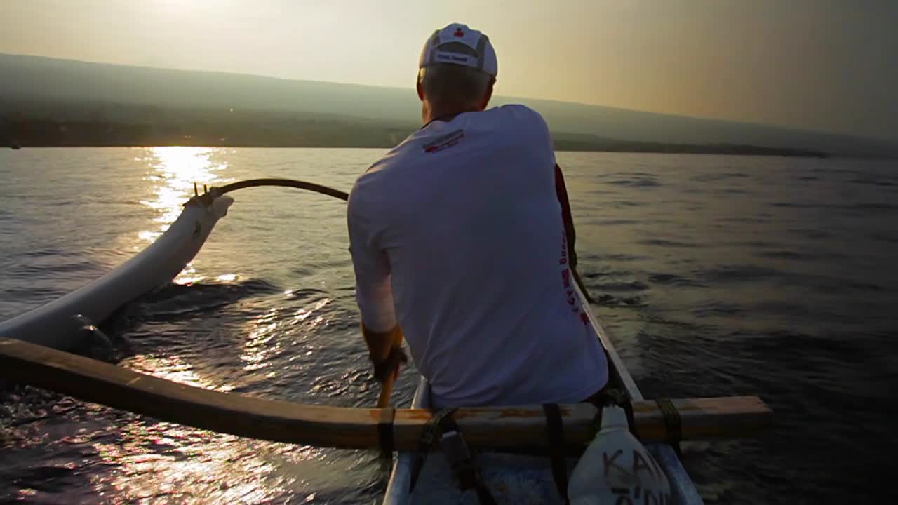 Slow motion of kayaks or outriggers rowing into sunset