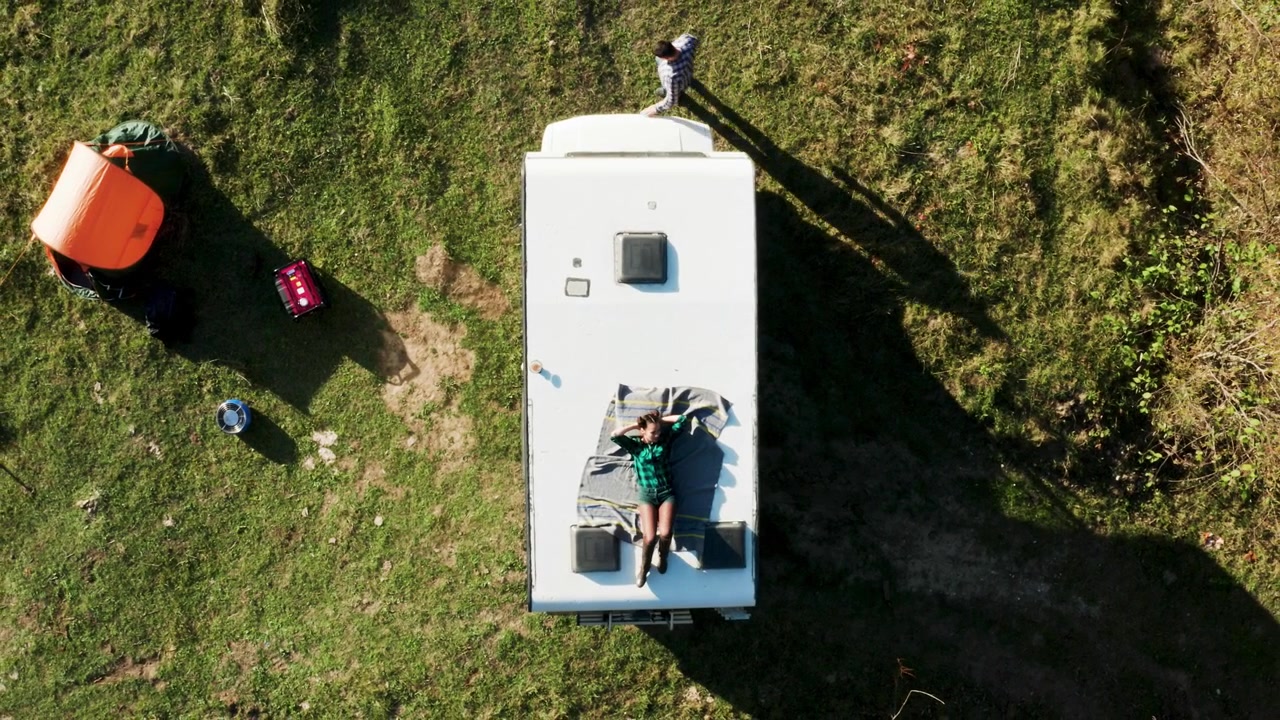 Vista aerea mostra una donna che si riposa sul tetto di un camper
