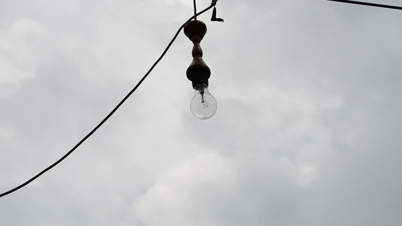 La lámpara incandescente contra el cielo. Lámpara en un cable
