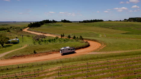 Toma-Aérea-Expedición-Camión-Conduciendo-Arena-Pista-Uruguay-Brasil-Frontera-Viñedo-Verde-Paisaje