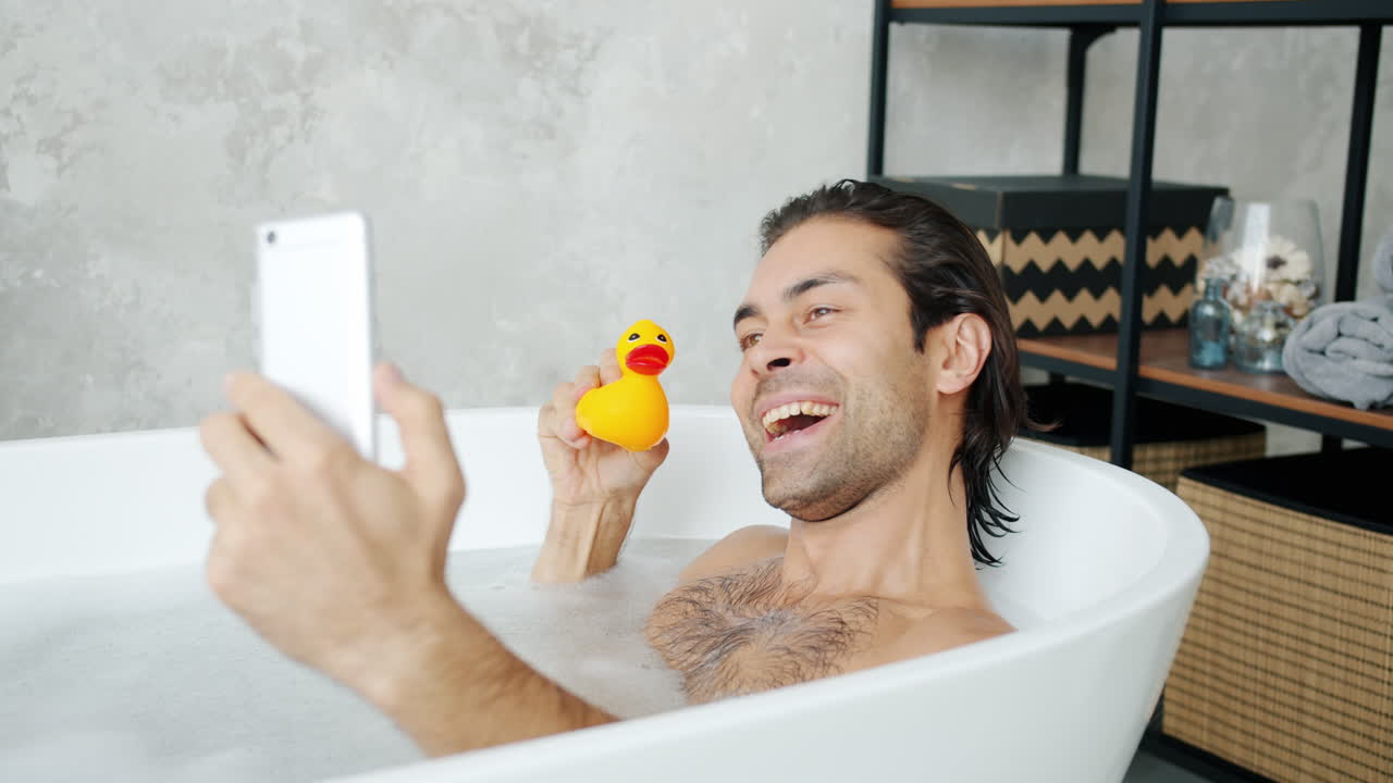 Man taking a Selfie in a Bathtub with a Rubber Duck