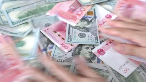 Chinese-and-American-paper-money,-close-up-female-hands-stirs-shuffles-cash-money-on-the-table,-concept-idea