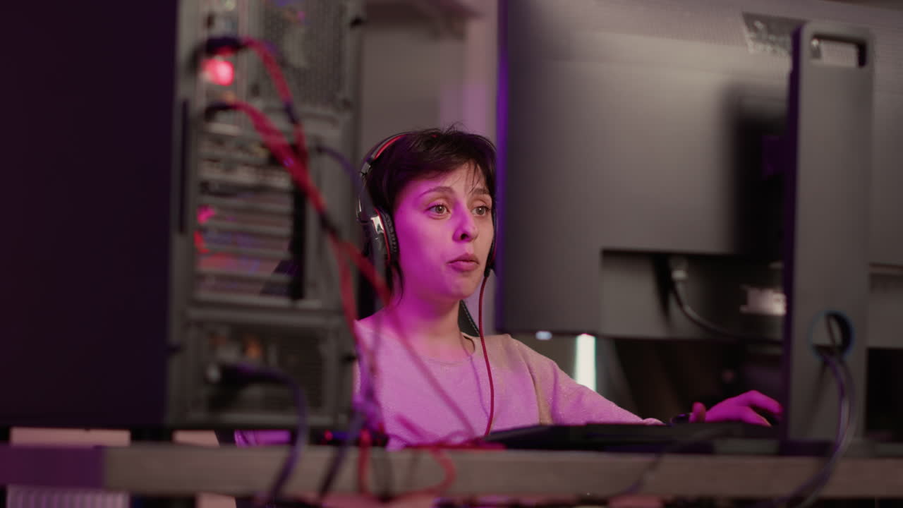 Handheld shot of streamer talking on headset to subscribers while online playing first person shooter