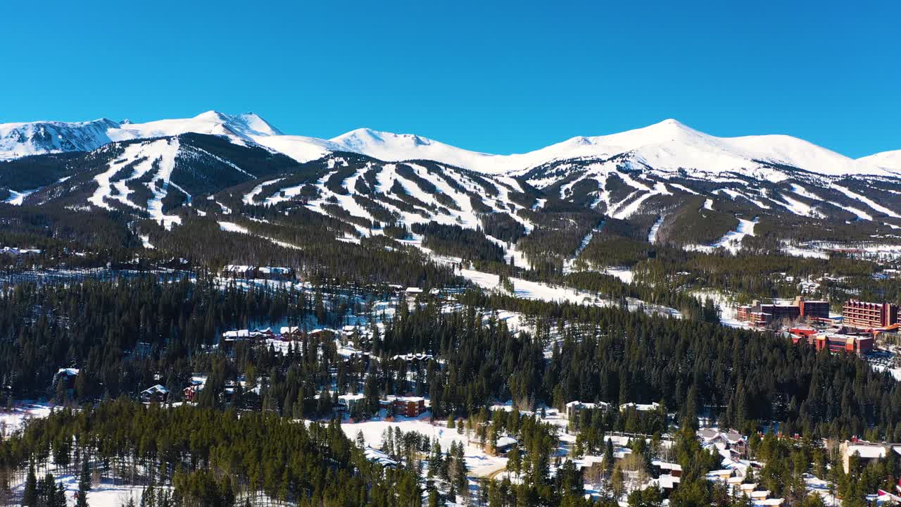 vista aérea de aviones no tripulados de las cimas de las montañas cubiertas de nieve en invierno con pistas de esquí listas para deportes al aire libre y aventura en el denso bosque de pinos