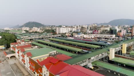 Vista-Aérea-De-La-Estación-De-Tren-En-El-Medio-De-La-Ciudad-India-De-Guwahati,-Largos-Trenes-Esperando-En-Las-Plataformas-Para-Que-Los-Pasajeros-Suban-A-Bordo