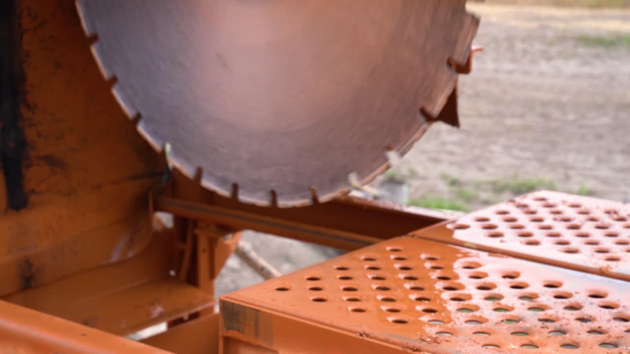 Spinning circular saw meant for cutting ceramic block at dusty outdoor construction site closeup
