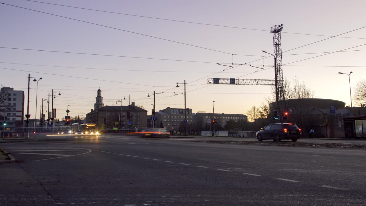 lapso de tiempo del tráfico de la hora pico de la ciudad sobre el puente del tranvía de liepaja, el paisaje de la ciudad después de la puesta del sol, las rayas de los semáforos, los tranvías en movimiento rápido, el tiro ancho bajo