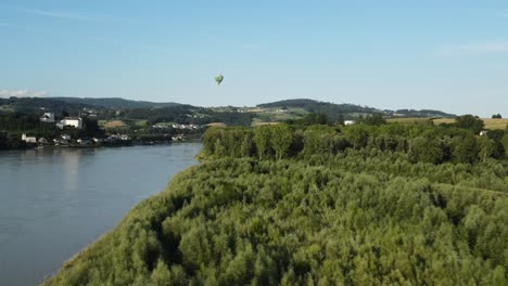 a hot air baloon climbing up above the countryside of upper austria