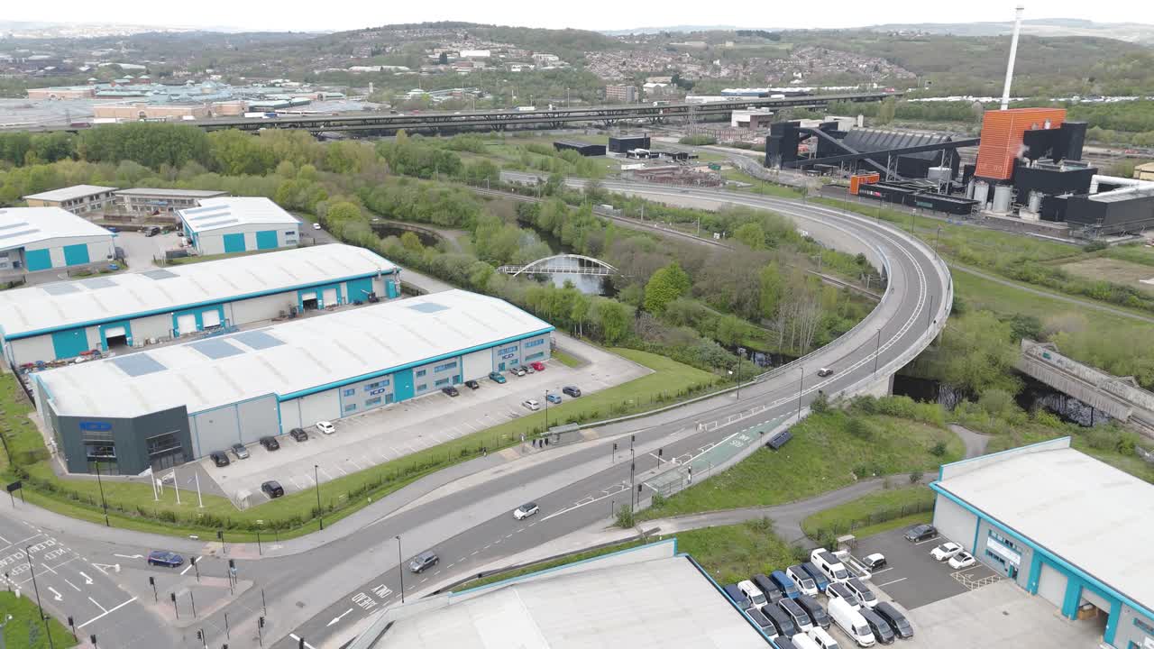 Ripresa aerea laterale con drone in cerchio della trafficata autostrada di Sheffield con fabbrica, auto, case, fiumi e aree pedonali. Cielo nuvoloso e coperto