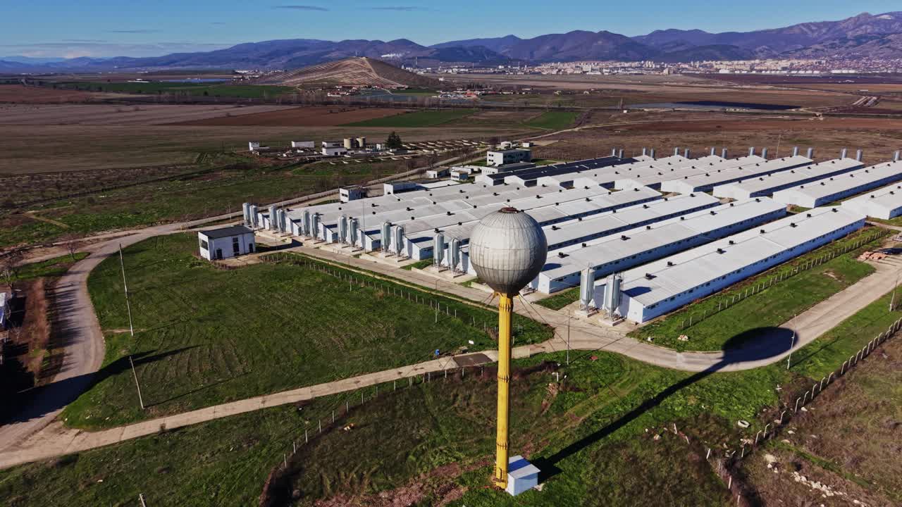 Sitio industrial con edificios grandes y una torre de agua cerca de una ciudad