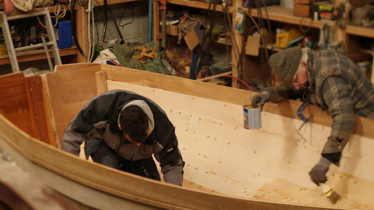 Woodworkers oiling interior of clinker lapstrake wood boat