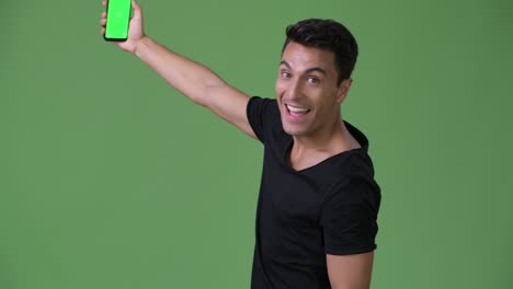 young handsome hispanic man against green background