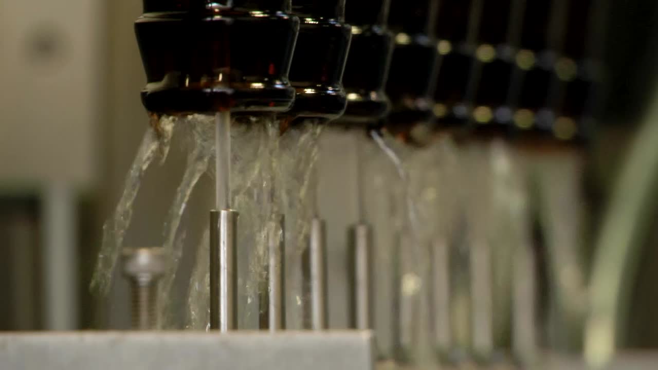 Beer bottles being washed upside down with jets of water before the bottling process